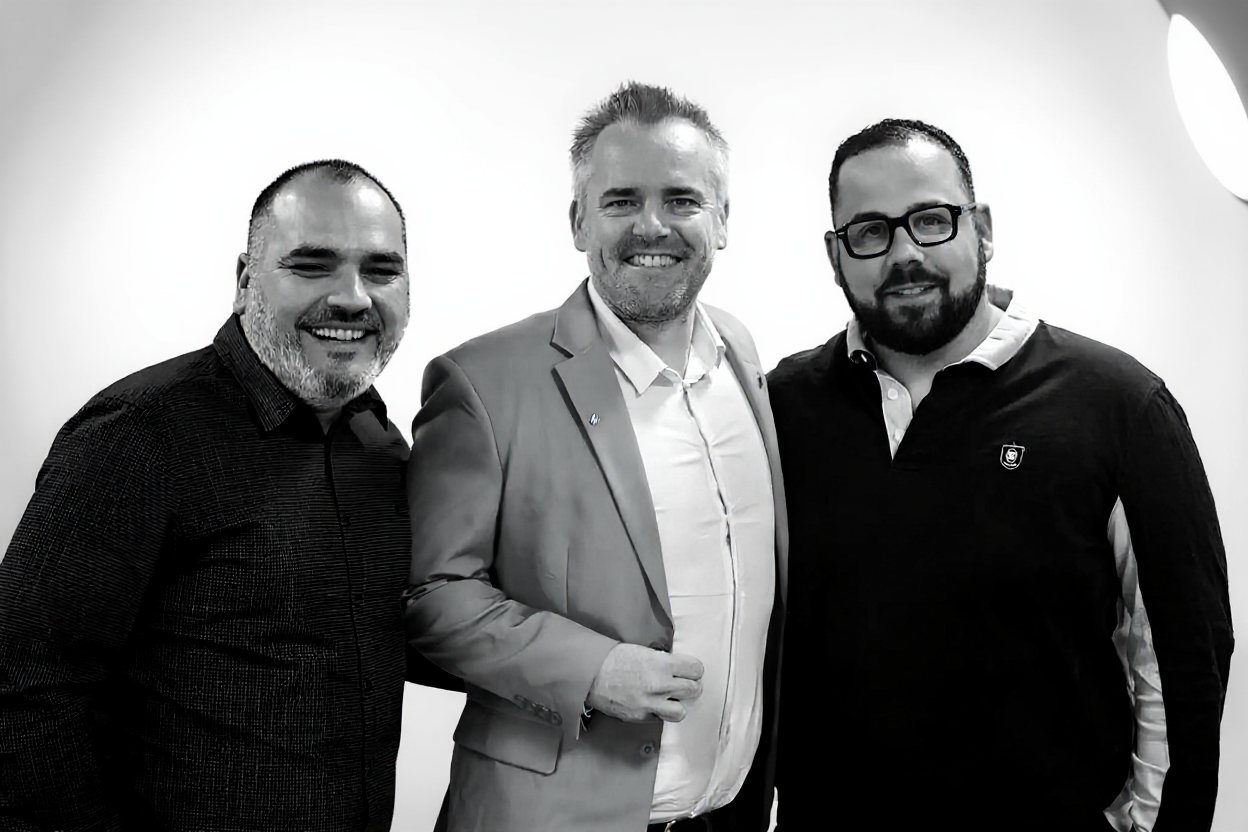 Les trois cofondateurs de Rayoneo, côte à côte et souriants, en noir et blanc.